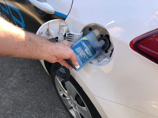 Person adding Cleanpower Fuel Treatment into gas tank